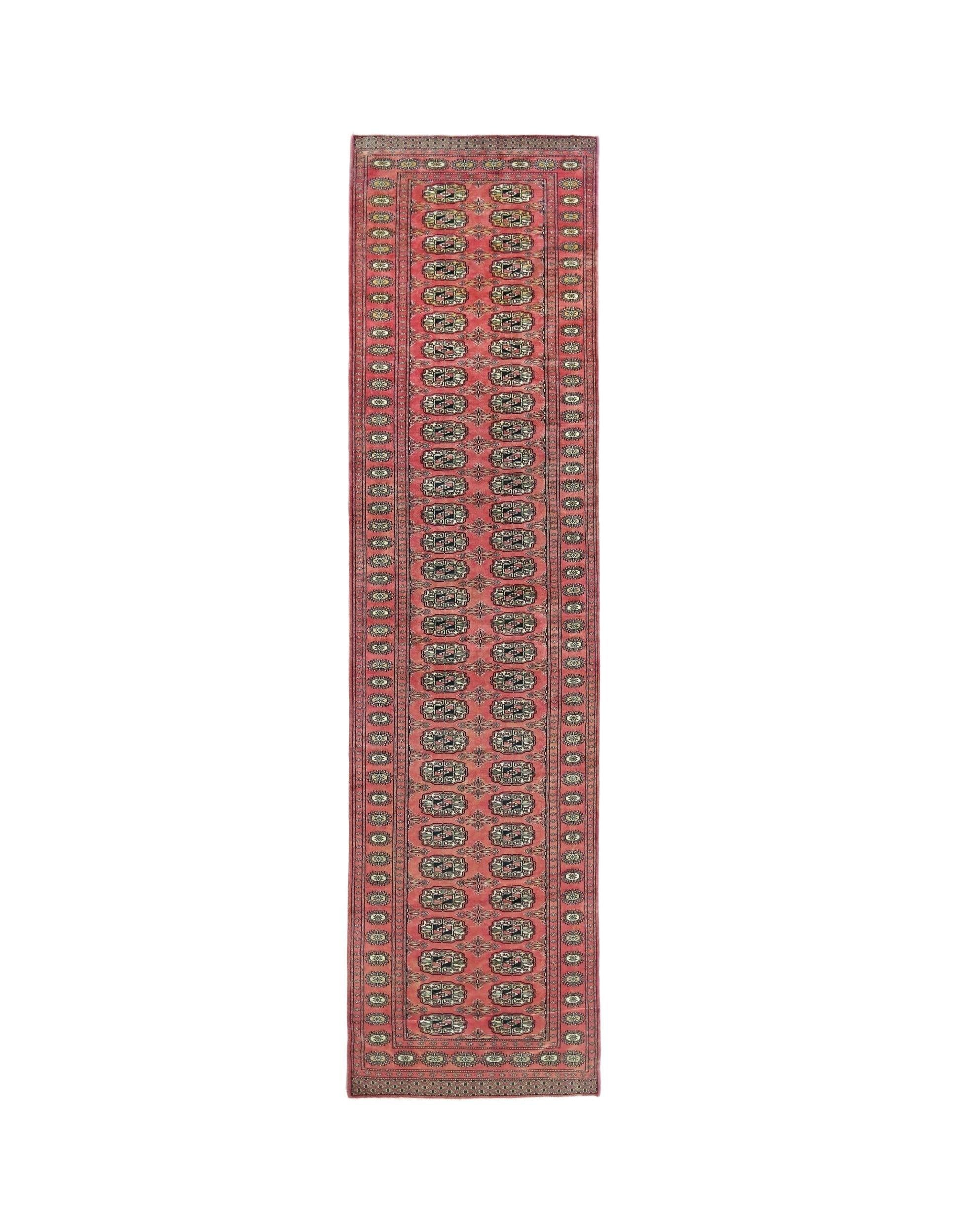 A vintage Pakistani runner rug featuring a repeating geometric pattern in red and cream tones.