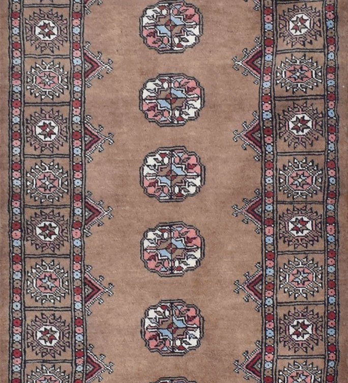 A handmade wool runner rug featuring a tan field with repeating geometric medallions and borders.