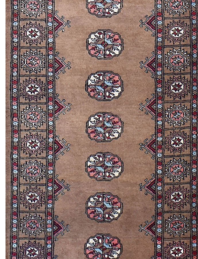 A handmade wool runner rug featuring a tan field with repeating geometric medallions and borders.