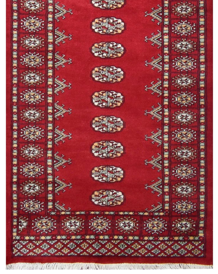 A handmade red wool runner rug featuring repeating Princess Bokhara geometric motifs.