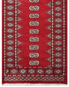 A handmade red wool runner rug featuring repeating Princess Bokhara geometric motifs.