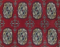 A vintage Pakistani runner rug featuring a repeating pattern of dark red octagonal guls and crosses.
