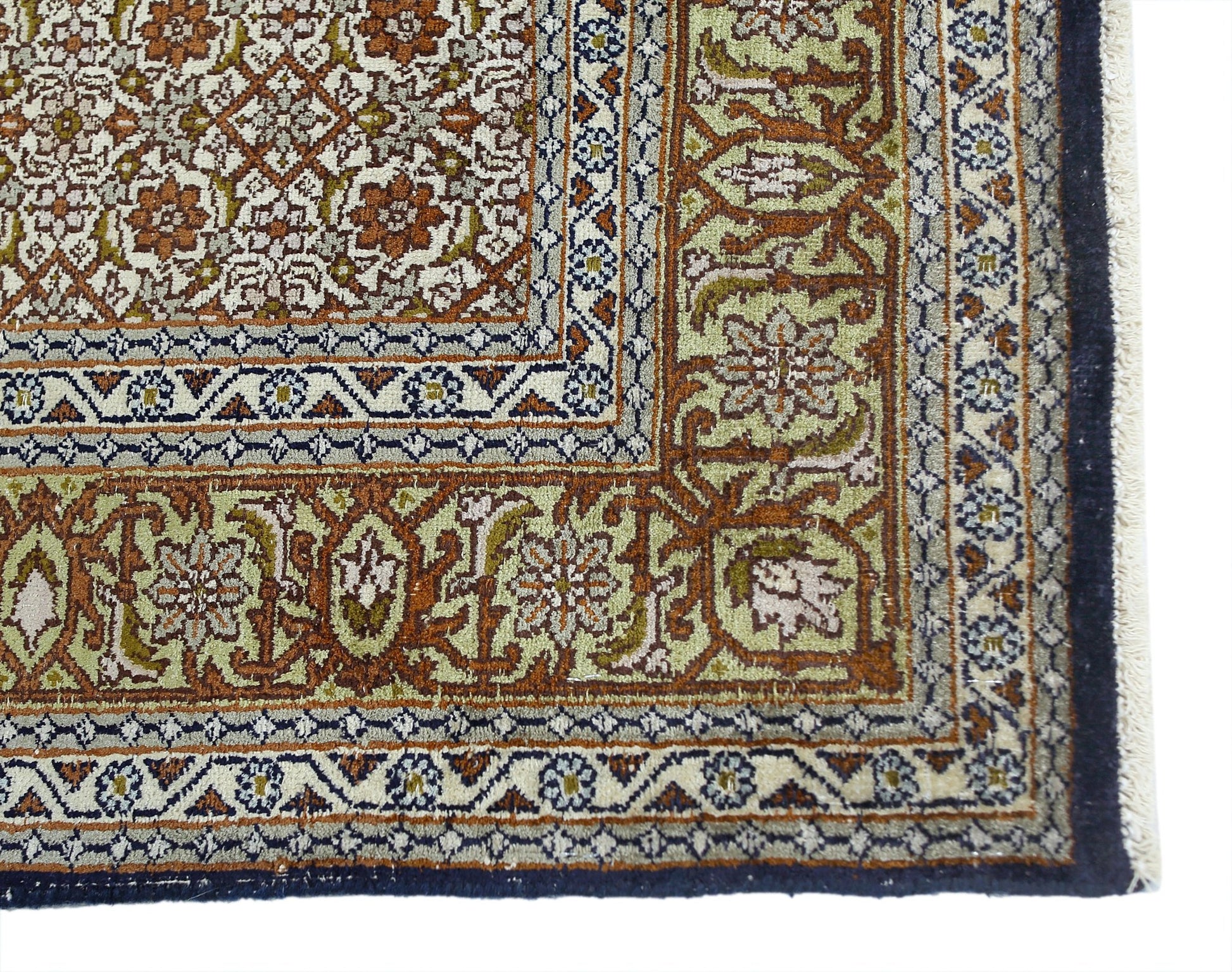 A vintage silk Kashmiri rug featuring intricate floral patterns in shades of green and rust.
