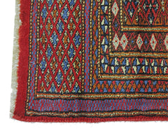 A vintage Pakistani Princess Bokhara rug featuring a geometric diamond pattern in red and blue.