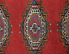 A vintage Pakistani Princess Bokhara rug featuring repeating geometric diamond motifs in red.