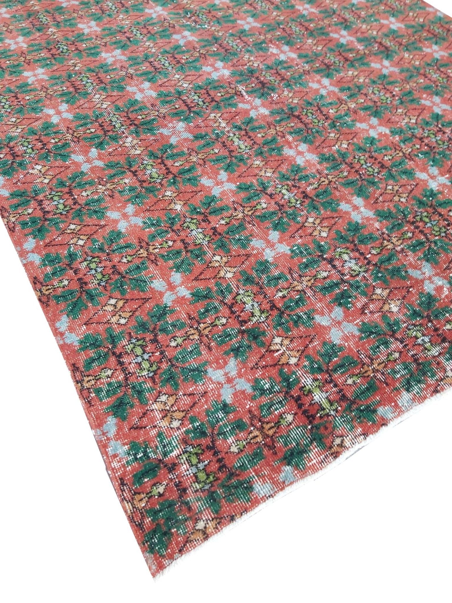 A vintage handmade Turkish wool rug featuring a repeating geometric pattern in red and green.