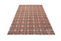 A vintage handmade Turkish rug featuring a repeating geometric pattern in shades of red and green.