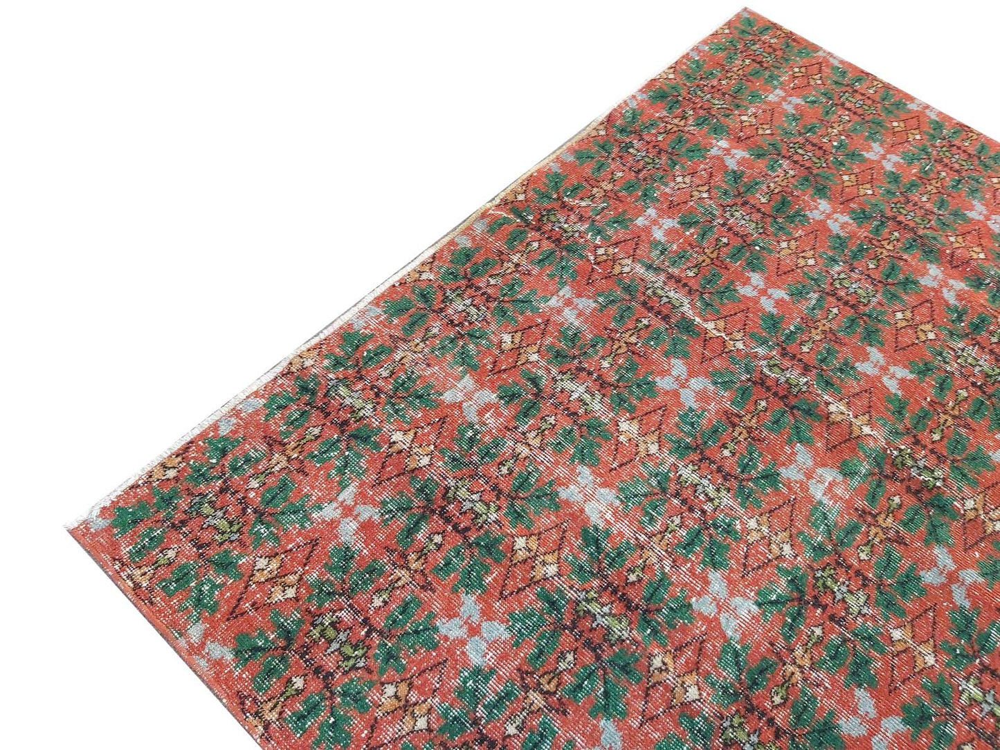 A vintage handmade Turkish wool rug featuring a repeating geometric pattern in red and green.