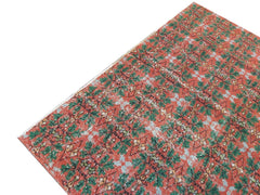 A vintage handmade Turkish wool rug featuring a repeating geometric pattern in red and green.