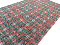 A vintage Turkish rug featuring a repeating geometric floral pattern in red, green, and blue.