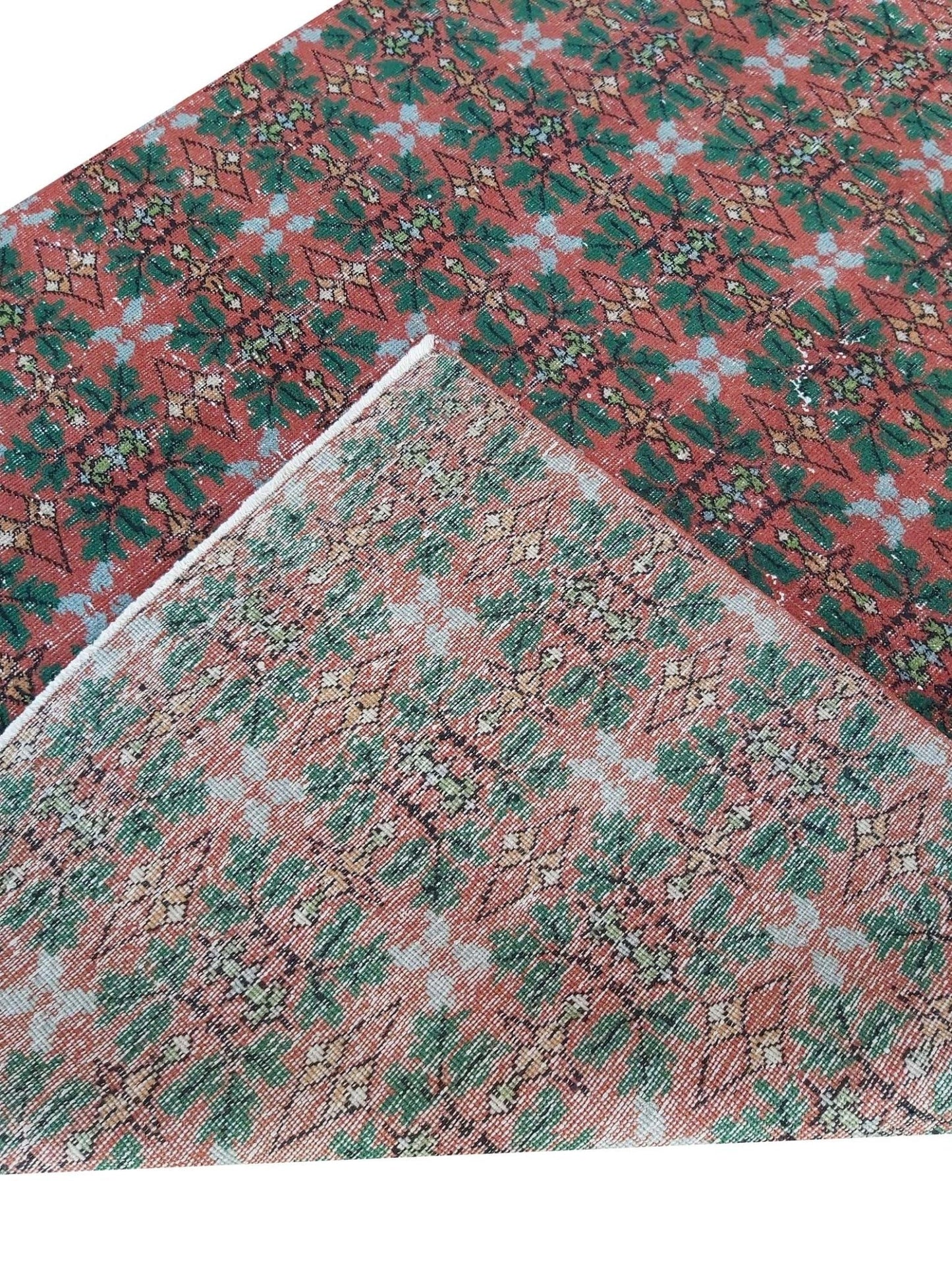 A vintage handmade Turkish wool rug featuring a repeating geometric pattern in red and green.