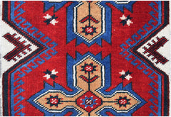 A handwoven vintage Turkish rug featuring a geometric floral pattern in red, blue, and tan.