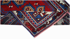 A handwoven vintage Turkish rug featuring geometric patterns in red, blue, and cream wool.