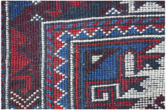 A close-up of a handwoven vintage Turkish rug featuring geometric patterns in red, blue, and white.