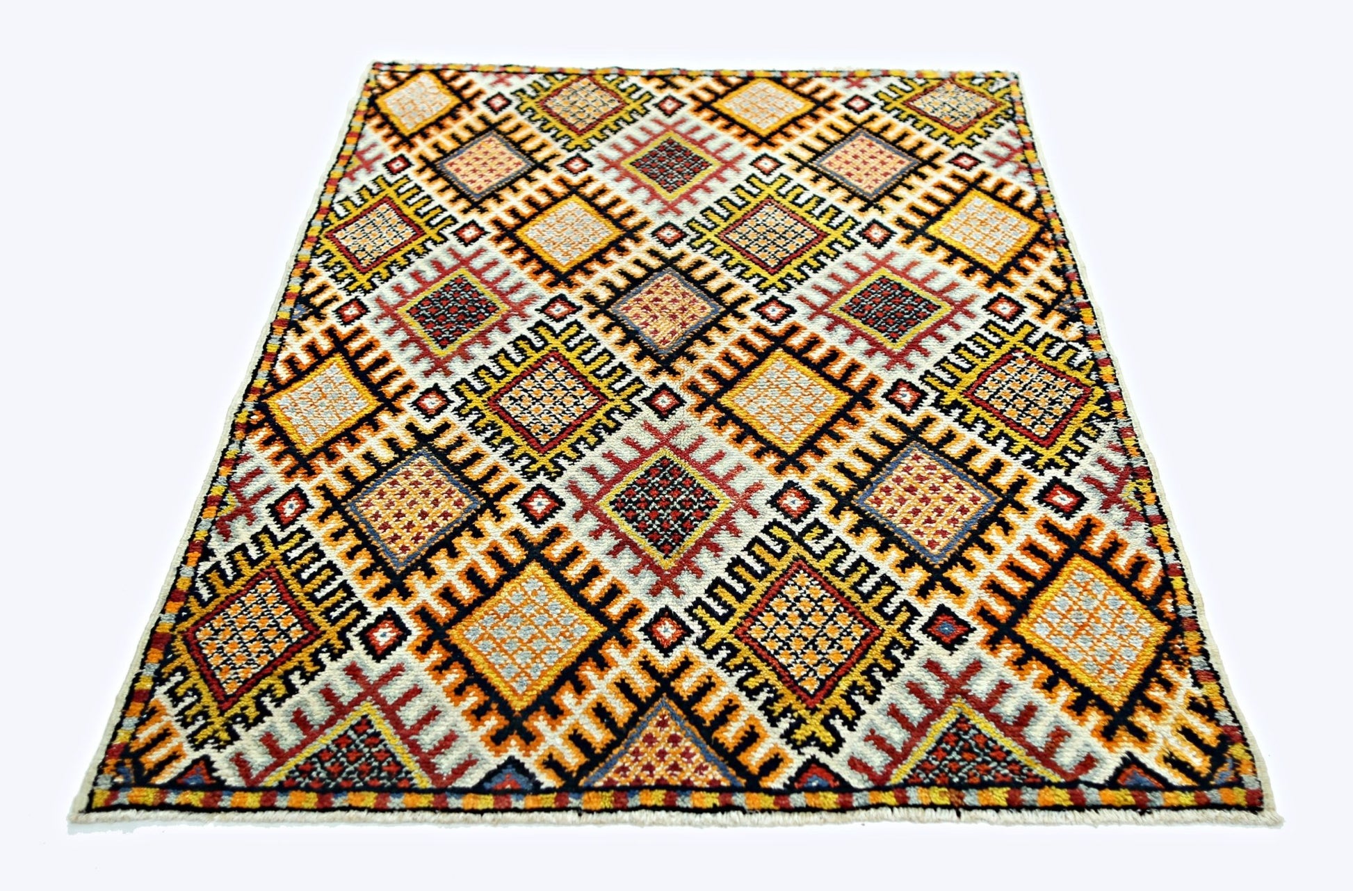 A vintage handmade Turkish rug featuring a repeating geometric diamond pattern in warm colors.