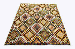A vintage handmade Turkish rug featuring a repeating geometric diamond pattern in warm colors.