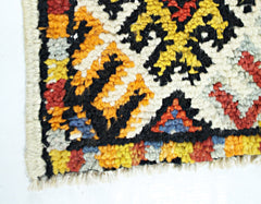 A close-up of a vintage handmade Turkish rug featuring a geometric pattern in wool.