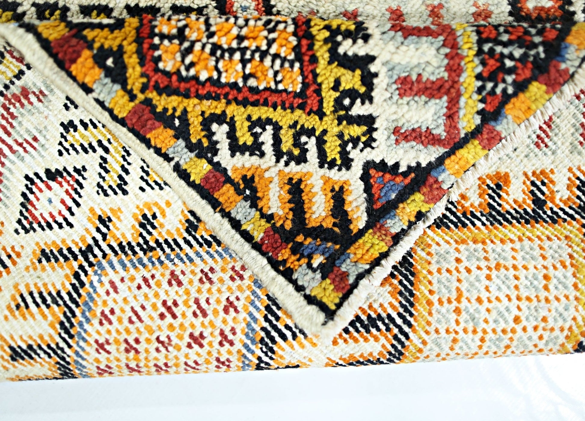 A close-up view of a vintage handmade Turkish wool rug featuring a colorful geometric pattern.