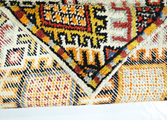 A close-up view of a vintage handmade Turkish wool rug featuring a colorful geometric pattern.