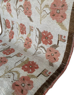 A vintage Turkish Oushak rug featuring a cream background with a pink floral tulip pattern.
