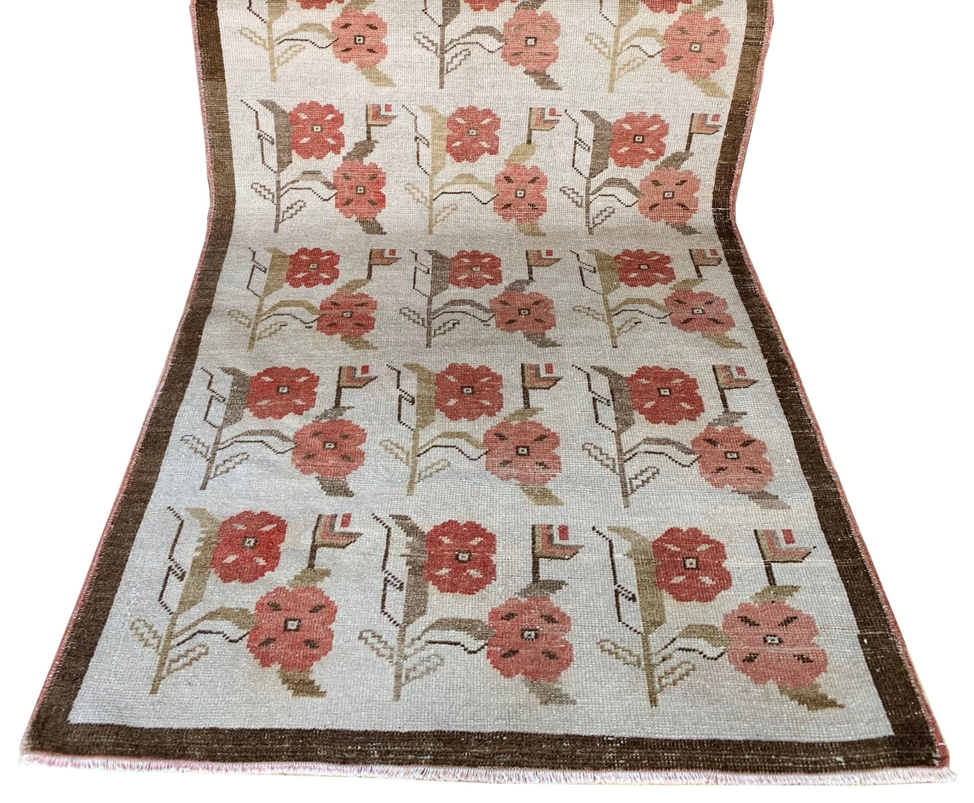 A vintage Turkish Oushak rug featuring a repeating floral tulip pattern in muted earth tones.