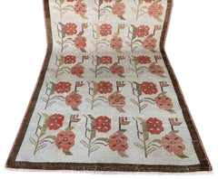 A vintage Turkish Oushak rug featuring a repeating floral tulip pattern in muted earth tones.