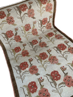 Vintage Turkish Oushak rug featuring a repeating floral tulip pattern in muted red and brown tones.
