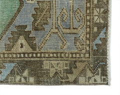 A close-up of a vintage Turkish rug featuring geometric patterns in muted blue, green, and brown.