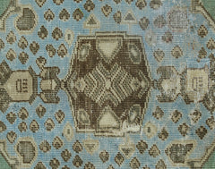 A vintage handmade Turkish rug featuring a geometric brown pattern on a faded blue background.
