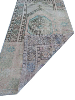 A vintage handmade Turkish wool rug with a faded geometric pattern and a folded corner.