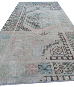 A vintage handmade Turkish wool rug featuring a faded geometric pattern in muted pastel tones.