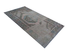 A vintage handmade Turkish wool rug featuring a faded geometric pattern in muted grey and blue tones.