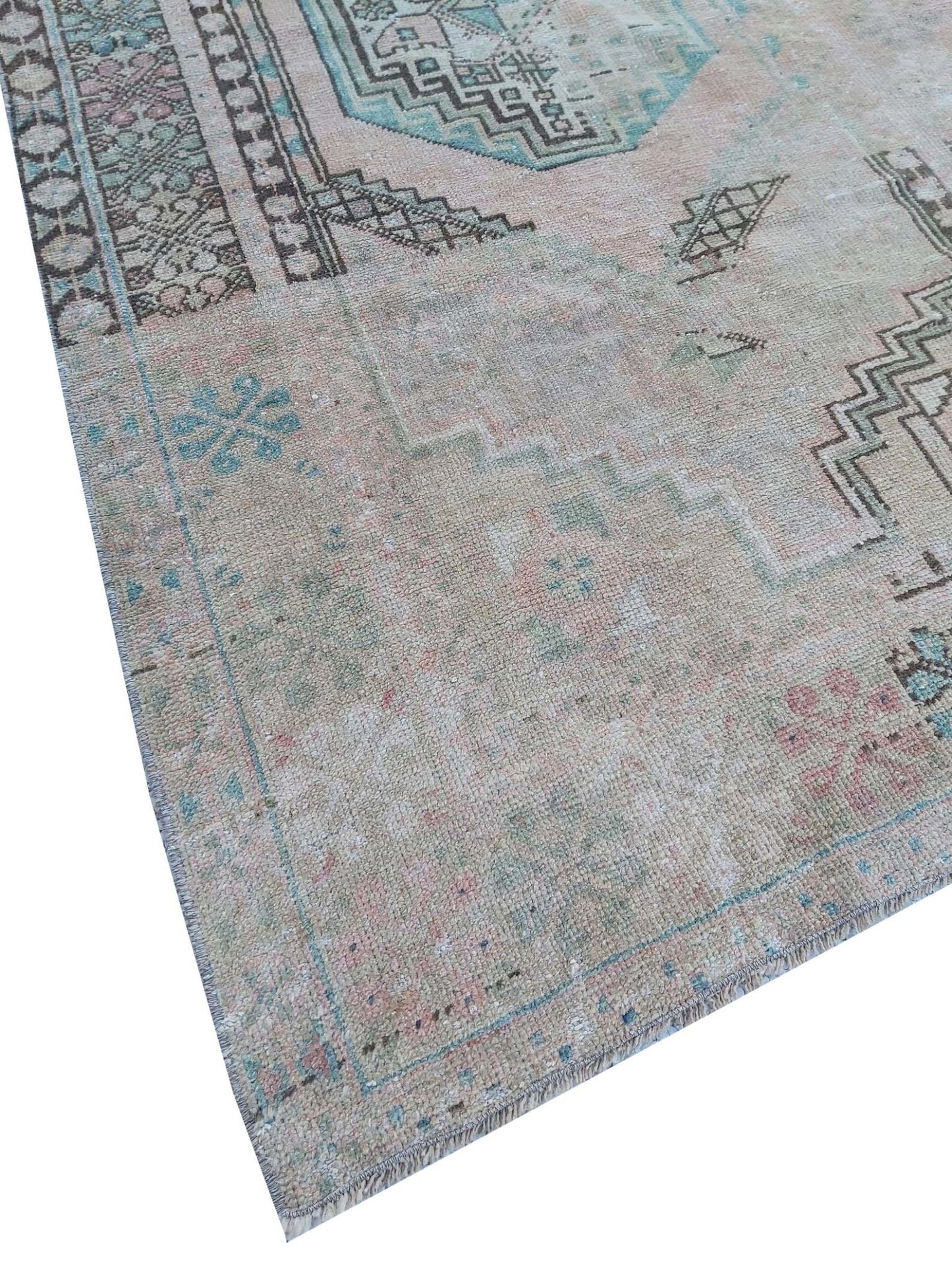 A vintage handmade Turkish wool rug featuring faded geometric patterns in soft pastel tones.