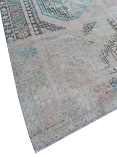 A vintage handmade Turkish wool rug featuring faded geometric patterns in soft pastel tones.