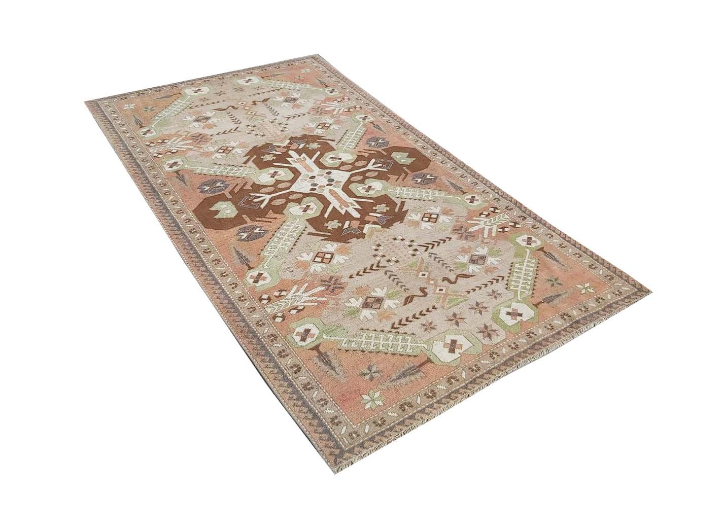 A vintage handmade Turkish rug featuring geometric patterns in shades of brown, green, and peach.