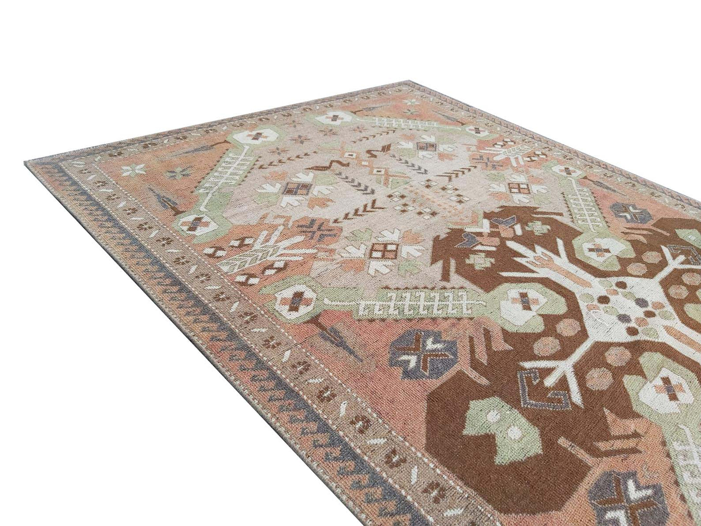 A vintage handmade Turkish rug featuring geometric patterns in shades of brown, green, and pink.
