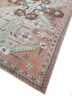 A vintage handmade Turkish rug featuring geometric patterns in shades of brown, green, and pink.