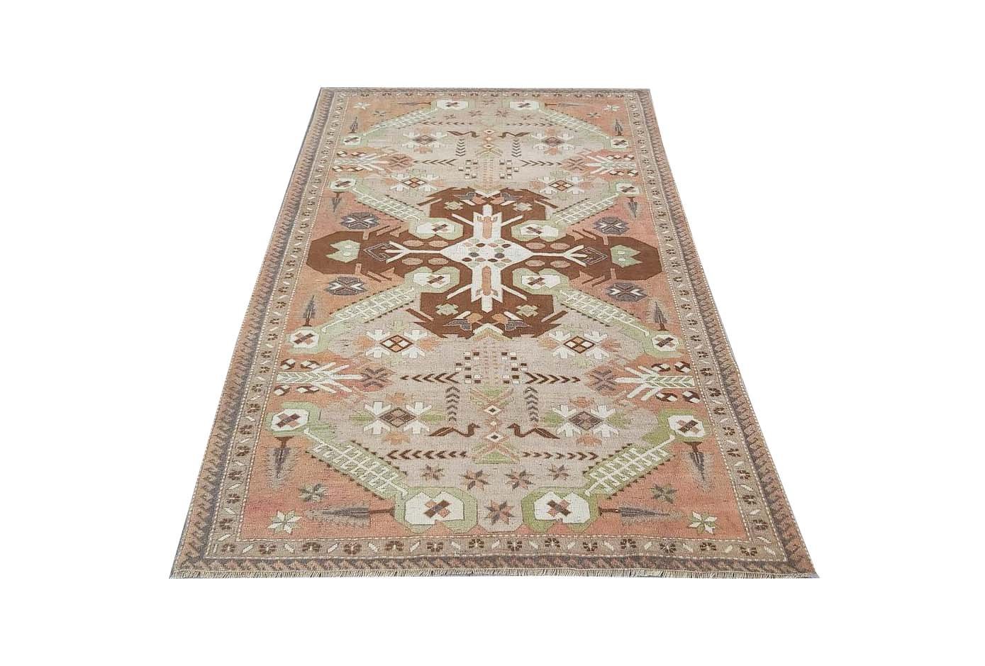 A vintage handmade Turkish rug from Kars featuring geometric patterns in brown and green tones.