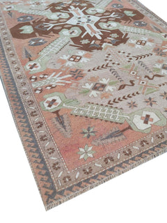 A vintage handmade Turkish wool rug featuring geometric patterns in brown, green, and peach tones.