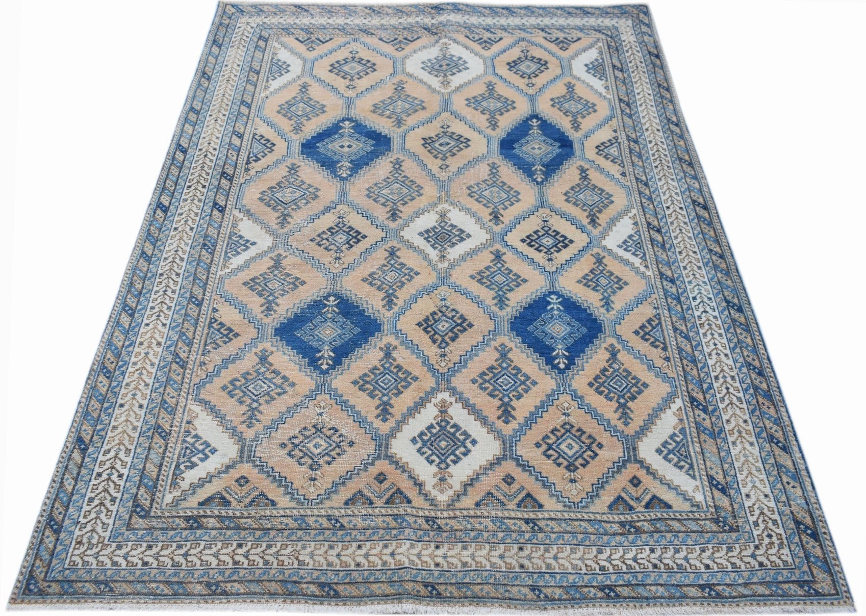 A vintage Persian rug featuring a geometric diamond pattern in shades of blue and beige.