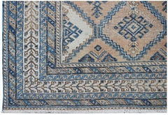 A vintage Persian rug featuring a traditional geometric pattern in shades of blue, tan, and cream.