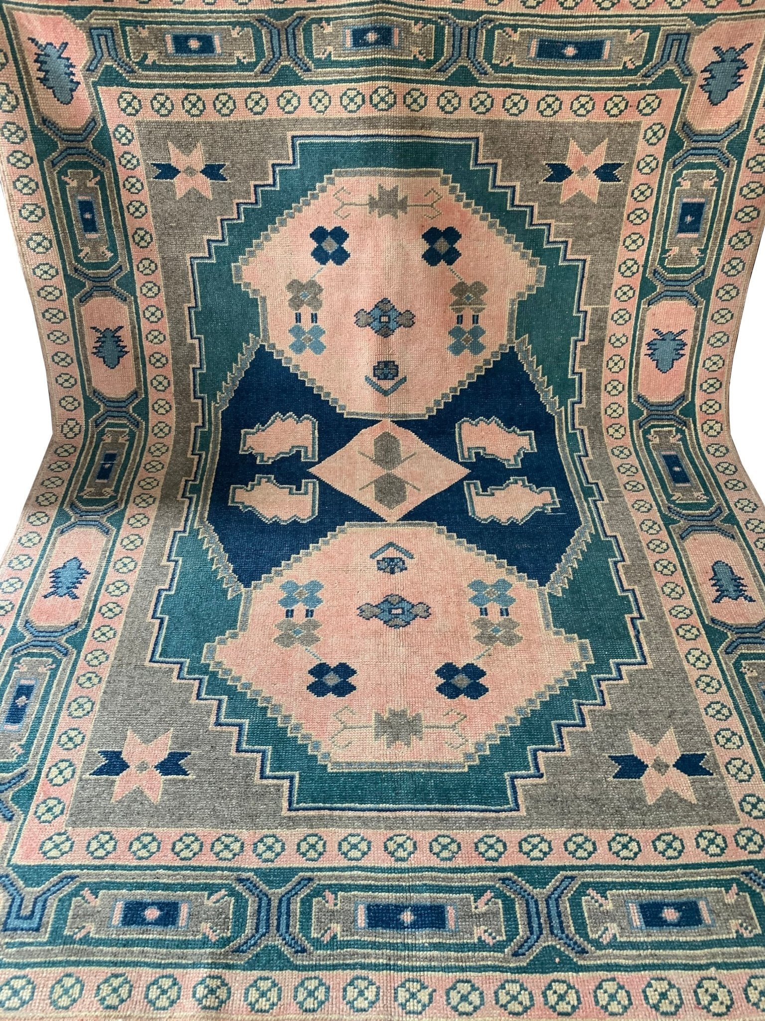 A handmade vintage Turkish Kars rug featuring geometric patterns in shades of pink, blue, and green.