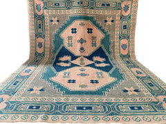A handmade vintage Turkish Kars rug featuring geometric patterns in shades of pink, green, and blue.