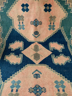 A handmade vintage Turkish Kars rug featuring geometric patterns in shades of pink, blue, and green.