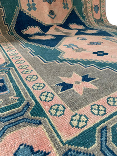 A handmade vintage Turkish rug from Kars featuring geometric patterns in pink, blue, and green.