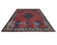 A vintage handmade Persian rug featuring a central blue medallion on a distressed red field.