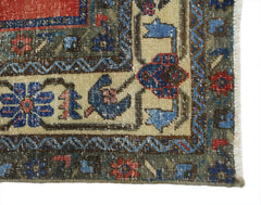 A corner detail of a vintage Persian rug featuring intricate floral patterns in red and blue.