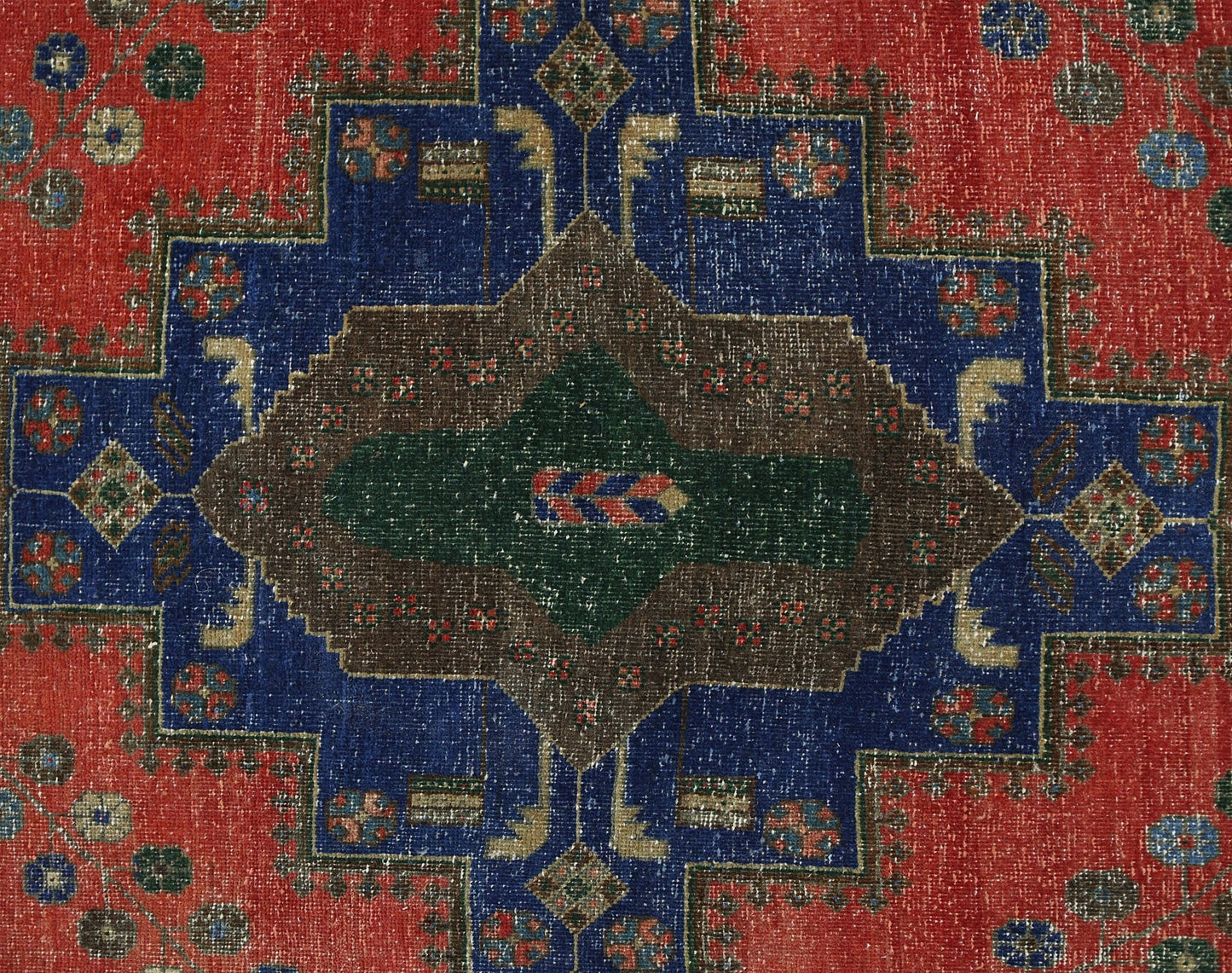A vintage Persian rug featuring a central geometric medallion in brown and green on a blue field.