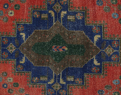 A vintage Persian rug featuring a central geometric medallion in brown and green on a blue field.