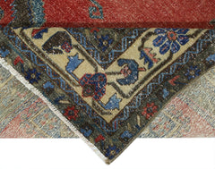 A corner of a vintage Persian rug is folded over to show its intricate floral pattern and weave.